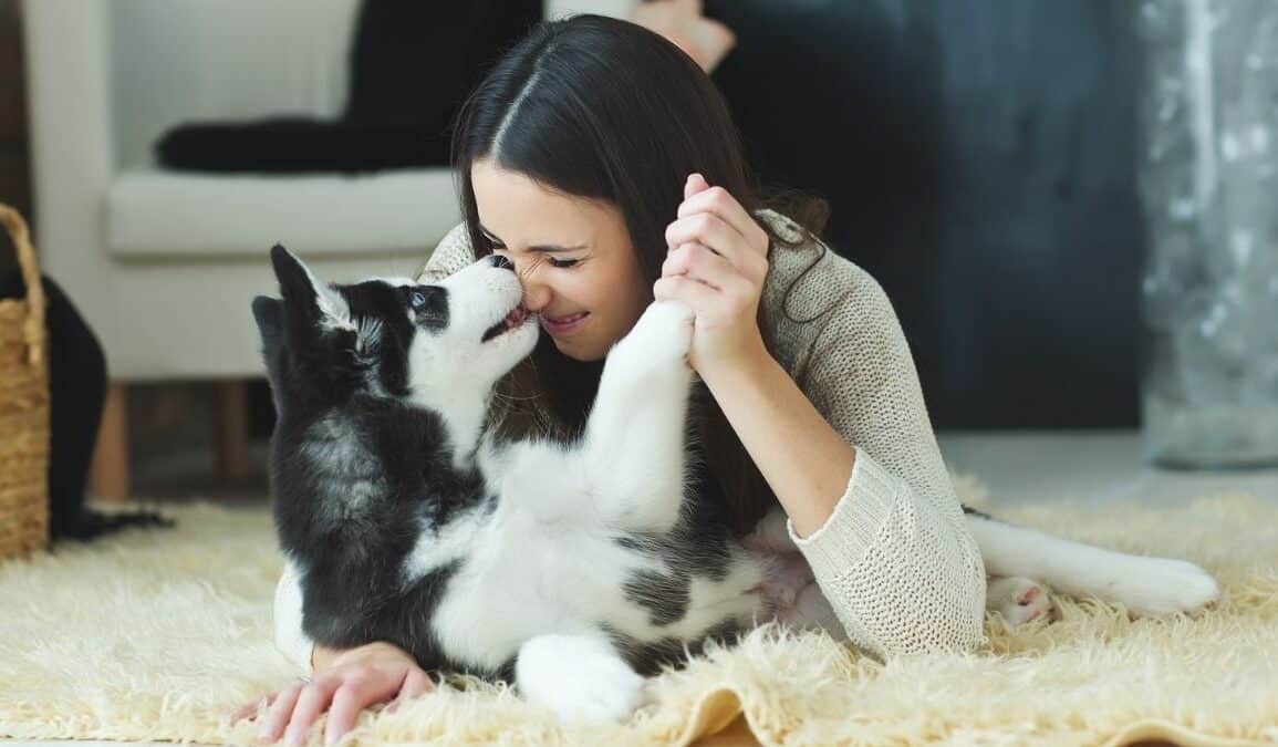 woman playing with dog on floor of room
