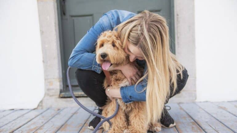 woman hugging labradoodle outside on deck